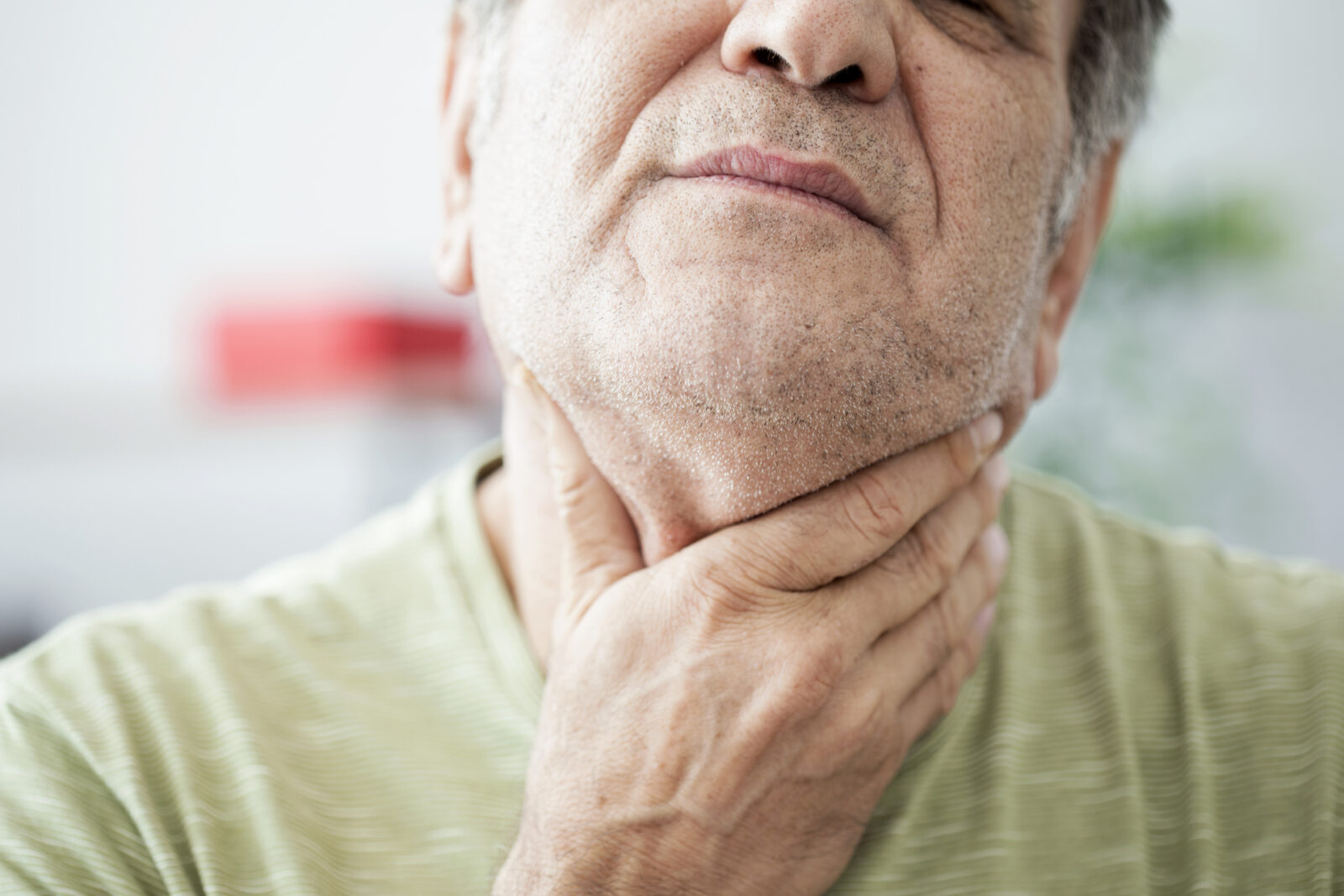 Man grabbing throat possibly dealing with Aging Voice