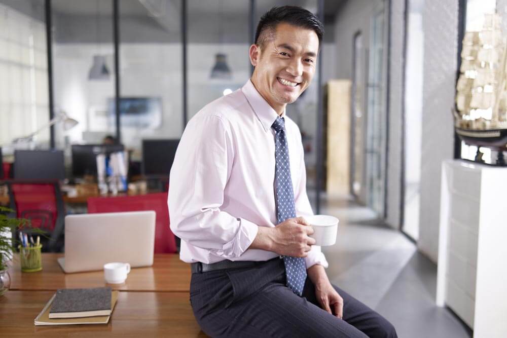 businessman holding cup of coffee sitting on desk