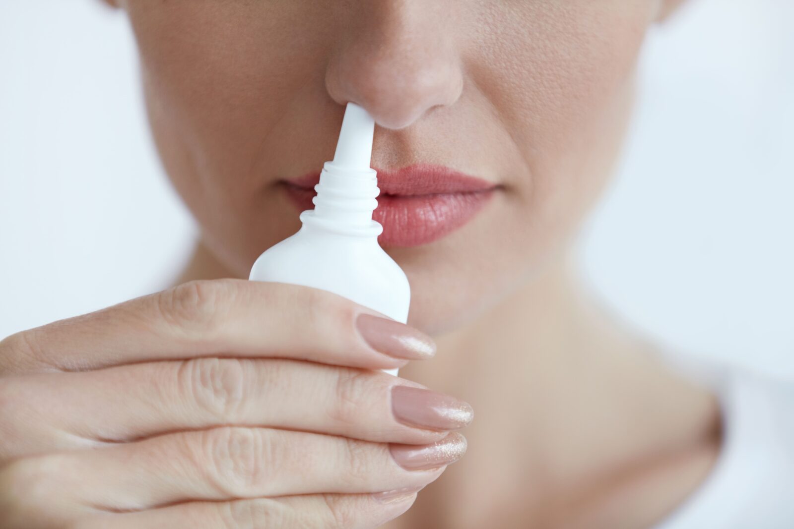close up of a woman using nasal spray