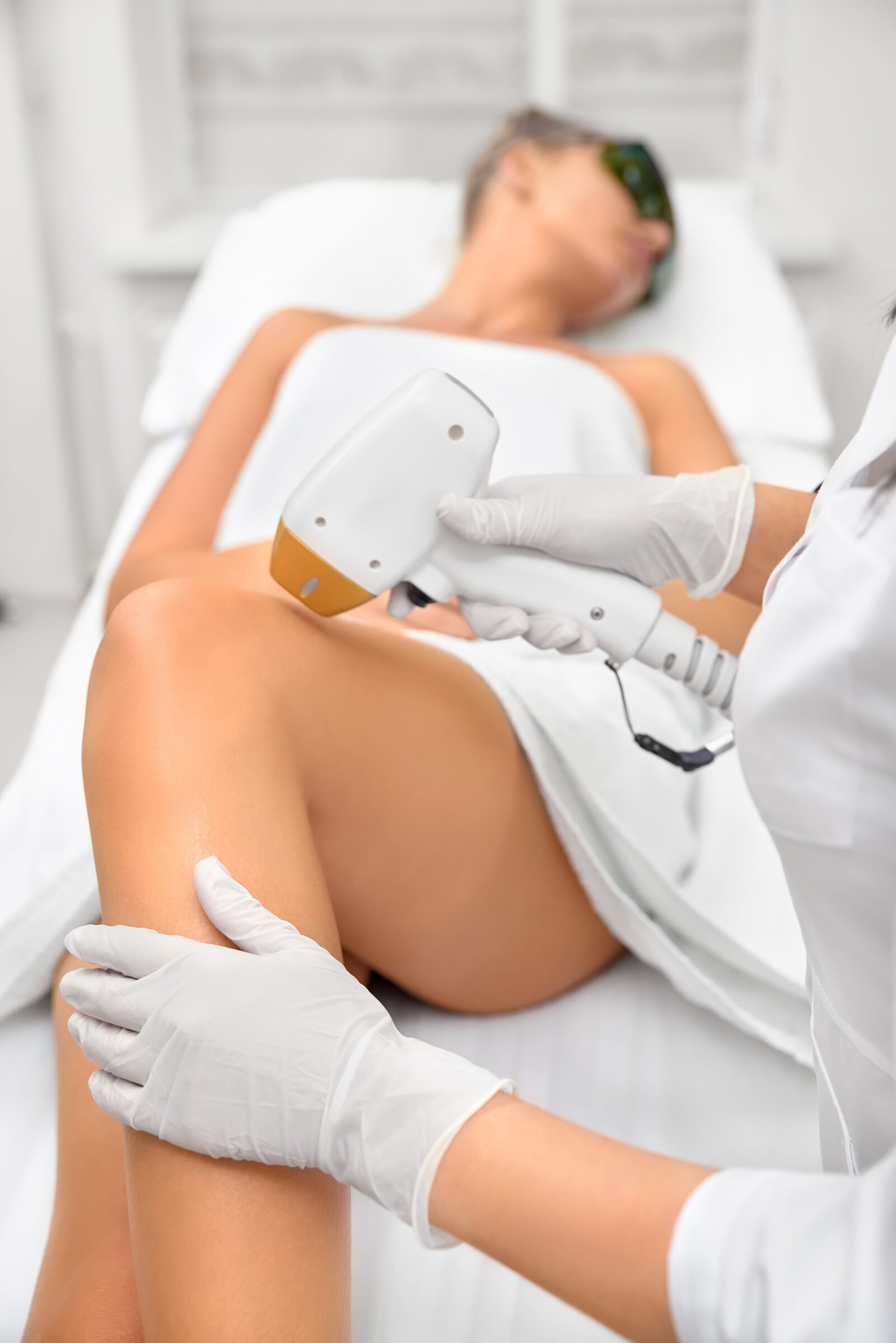 woman laying on spa table having laser hair removal performed on her legs
