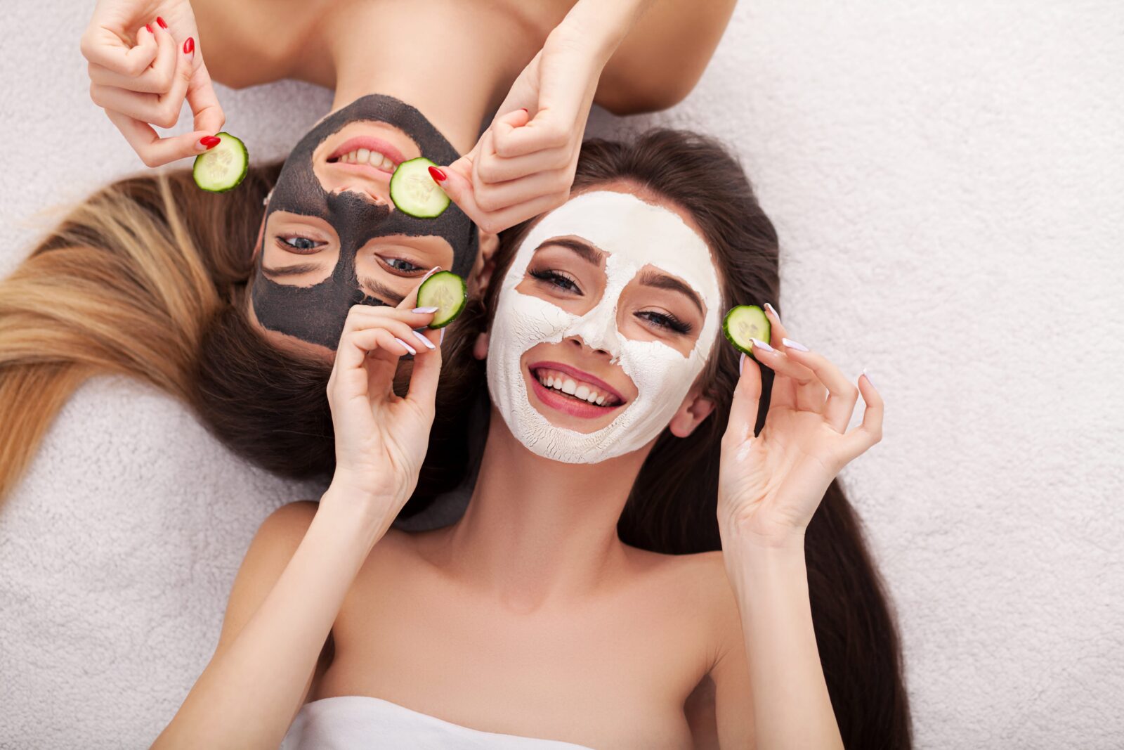 A picture of two girls friends relaxing with facial masks on over white background
