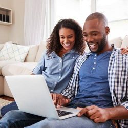 couple using laptop sitting on the floor at home